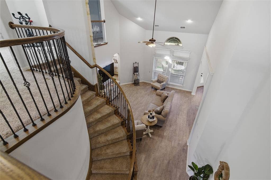 Carpeted curved staircase with decorative wrought iron balusters and wood handrails