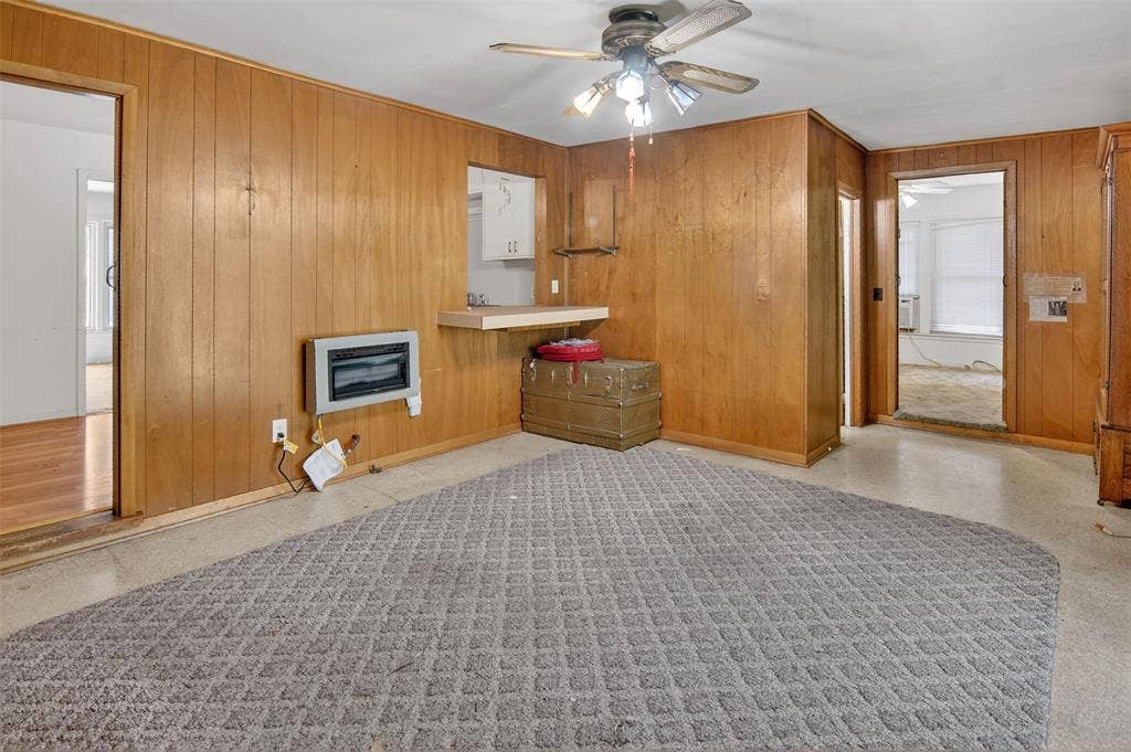 1224 S Brazos Street, Weatherford, TX 76086 Den features paneling on walls, a ceiling fan, and a heating unit.