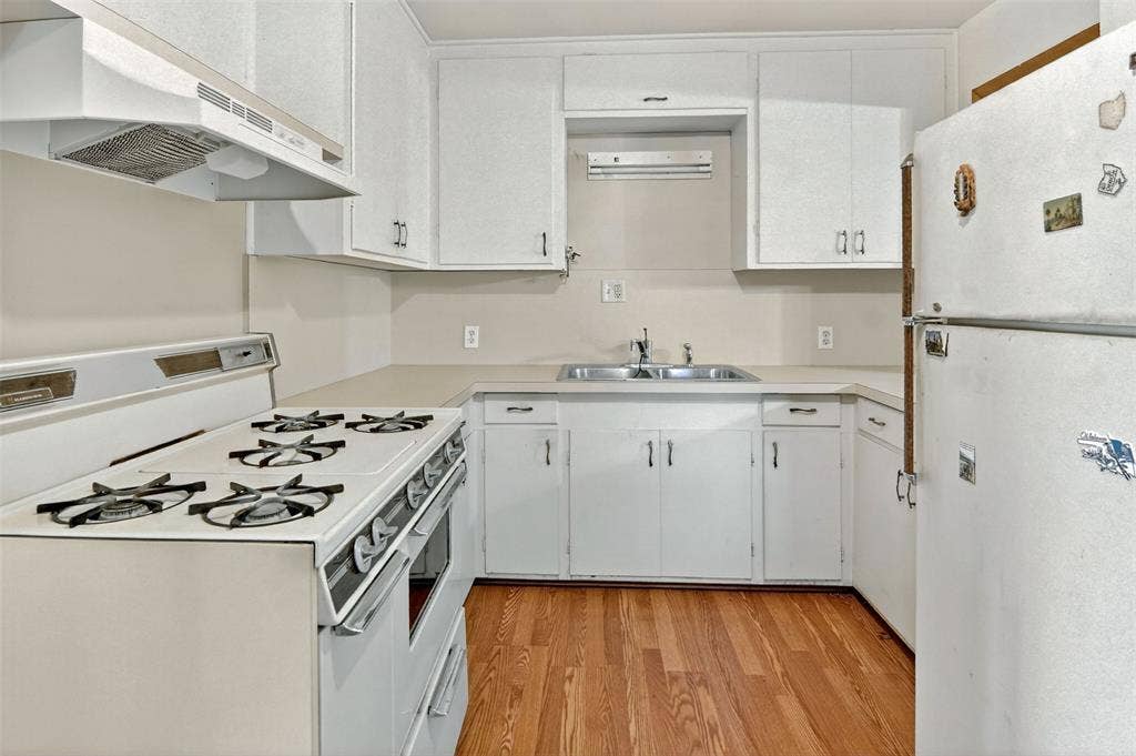 1224 S Brazos Street, Weatherford, TX 76086 Kitchen featuring white appliances, light countertops, white cabinetry, and light wood-style floors.
