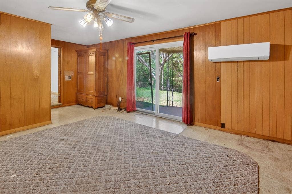 1224 S Brazos Street, Weatherford, TX 76086 Den with ceiling fan, wood panelling, carpet, and sliding glass door to large backyard.