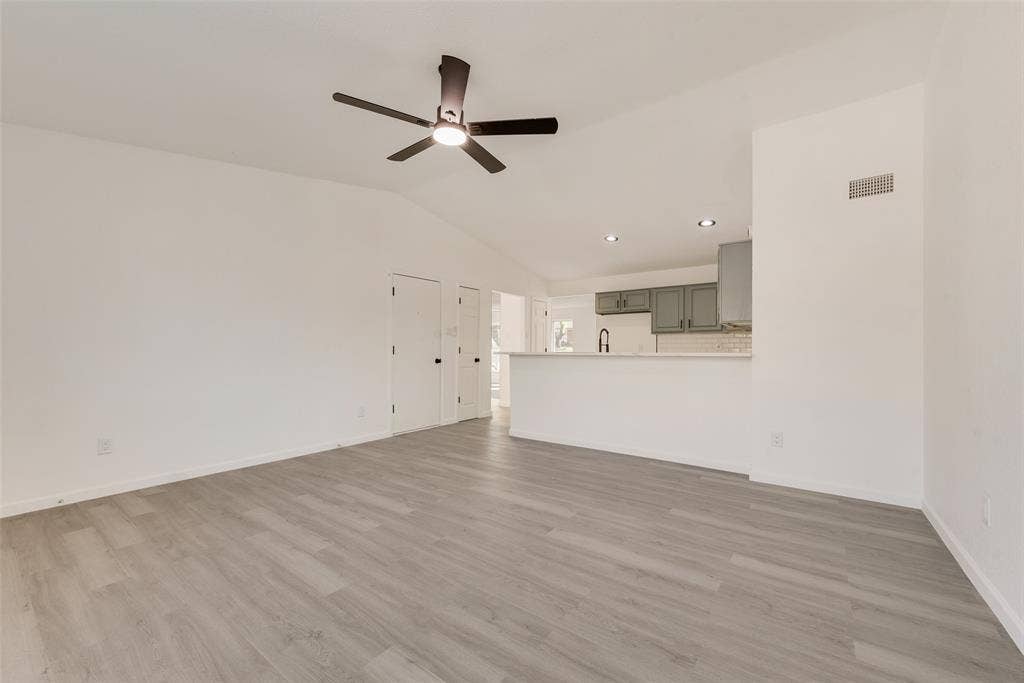 3217 Mahan Circle, Mesquite, TX 75149 Unfurnished living room featuring a ceiling fan, vaulted ceiling, and light wood-style flooring
