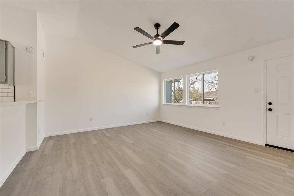 3217 Mahan Circle, Mesquite, TX 75149 Unfurnished living room featuring light wood-style flooring, lofted ceiling, and a ceiling fan