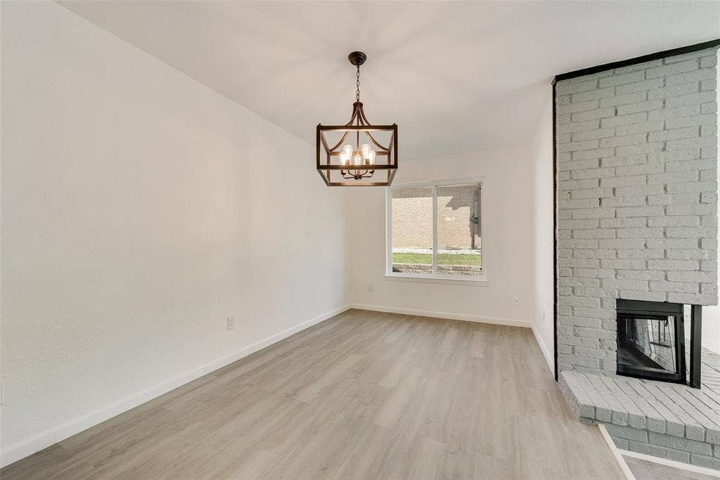 3217 Mahan Circle, Mesquite, TX 75149 Unfurnished dining room featuring light wood-type flooring, a brick fireplace, and suspended lighting