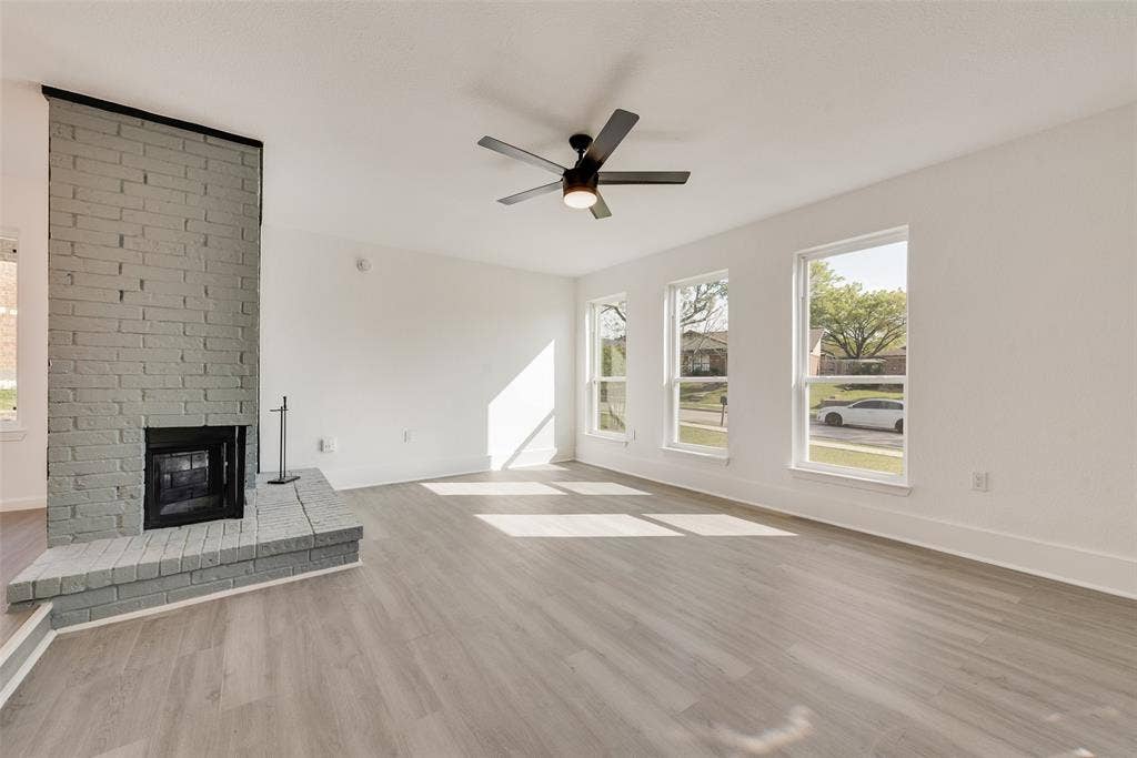 3217 Mahan Circle, Mesquite, TX 75149 Unfurnished living room featuring a brick fireplace, light wood finished floors, and a ceiling fan