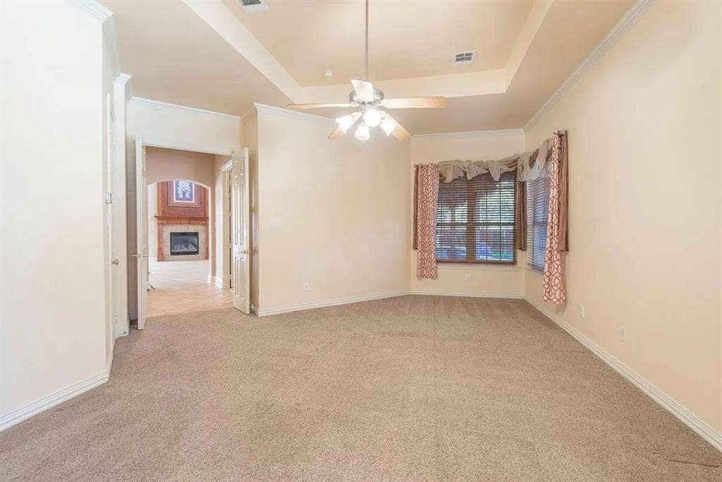 15031 Woodbluff Drive, Frisco, TX 75035 Carpeted room featuring a ceiling fan, tray ceiling, bay window, and arched doorway