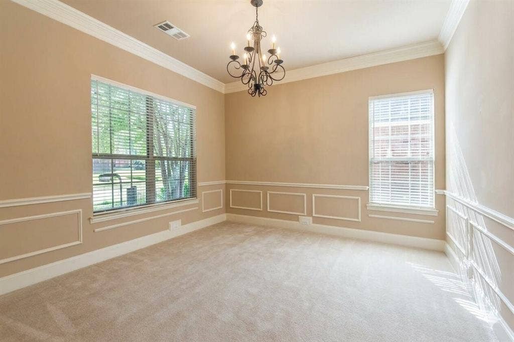 15031 Woodbluff Drive, Frisco, TX 75035 Spacious room featuring neutral carpeting, decorative wainscoting, crown molding, and an ornate wrought-iron chandelier