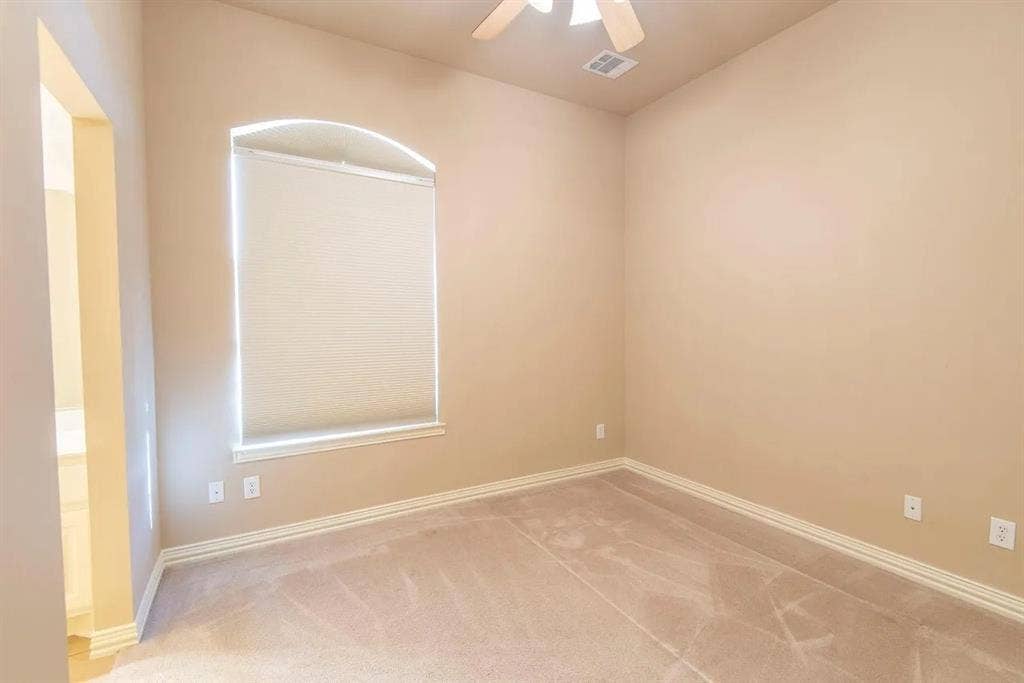 15031 Woodbluff Drive, Frisco, TX 75035 Room featuring a wide arched window with a roller shade, light neutral wall paint, carpet flooring, a ceiling fan, and white baseboards