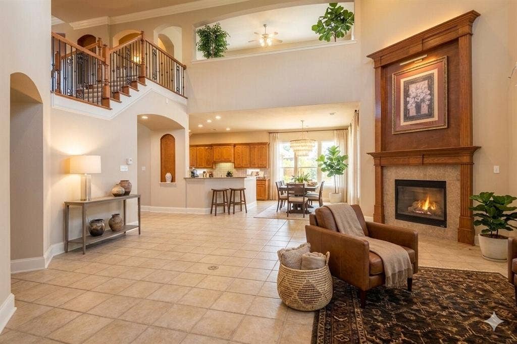 15031 Woodbluff Drive, Frisco, TX 75035 Two-story living area featuring a prominent fireplace with a wood mantle surround, tile hearth, and an open-concept layout