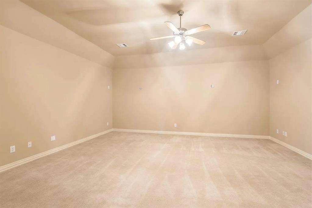 15031 Woodbluff Drive, Frisco, TX 75035 Spacious room featuring neutral carpeting, light beige wall paint, a tray ceiling, and a ceiling fan with integrated lighting