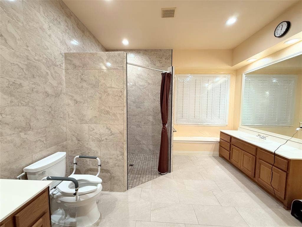 15031 Woodbluff Drive, Frisco, TX 75035 Spacious bathroom featuring a large walk-in shower with tiled walls, a double vanity with ample storage, a built-in window seat, and light-toned floor tiling