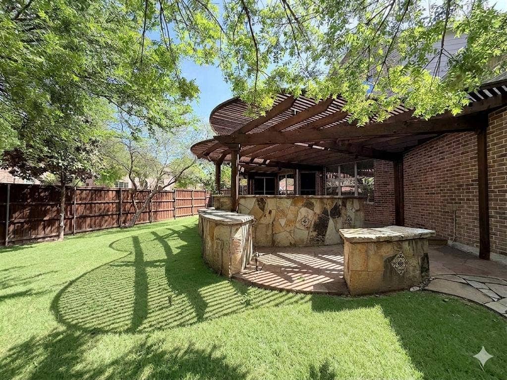 15031 Woodbluff Drive, Frisco, TX 75035 Expansive backyard featuring a manicured lawn, a full wooden privacy fence, and mature trees