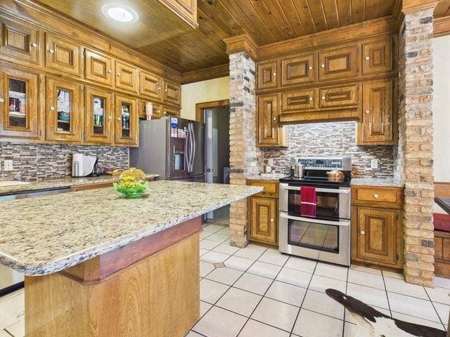 2382 Crystal Drive, Athens, TX 75752 Kitchen featuring appliances with stainless steel finishes, wood ceiling, light tile patterned flooring, backsplash, and brown cabinetry