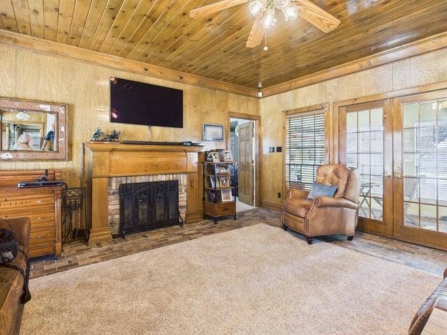 2382 Crystal Drive, Athens, TX 75752 Carpeted living room with wood ceiling, a ceiling fan, a fireplace, wooden walls, and crown molding