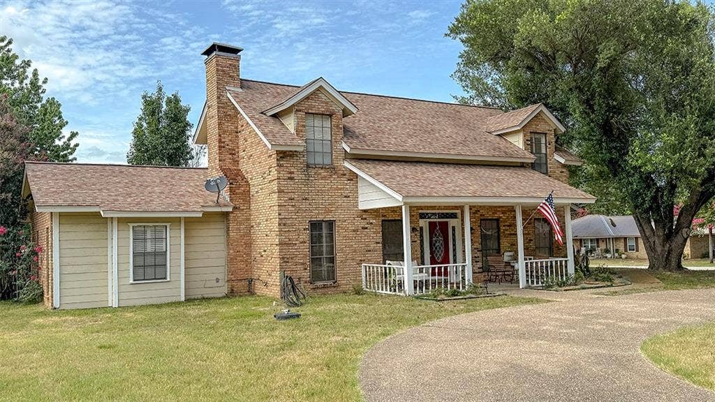 2382 Crystal Drive, Athens, TX 75752 View of front facade featuring a porch, roof with shingles, a chimney, a front lawn, and brick siding