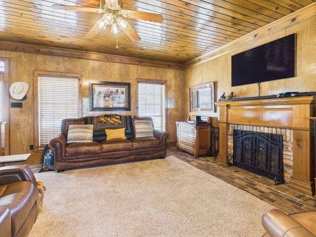 2382 Crystal Drive, Athens, TX 75752 Living room featuring wooden ceiling, ornamental molding, wooden walls, a ceiling fan, and a fireplace