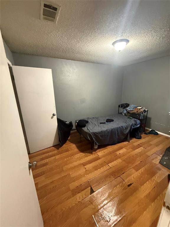 6036 Harrison Way, Watauga, TX 76148 Bedroom with a textured ceiling and wood finished floors