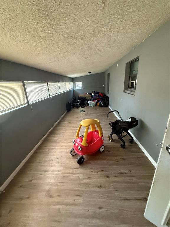 6036 Harrison Way, Watauga, TX 76148 Playroom with light wood finished floors and a textured ceiling