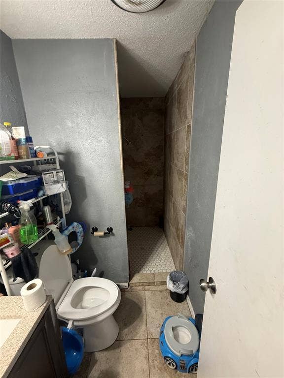 6036 Harrison Way, Watauga, TX 76148 Full bathroom with a textured ceiling, vanity, a shower stall, and light tile patterned flooring