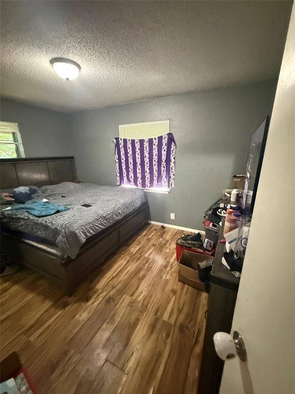 6036 Harrison Way, Watauga, TX 76148 Bedroom with light wood finished floors and a textured ceiling