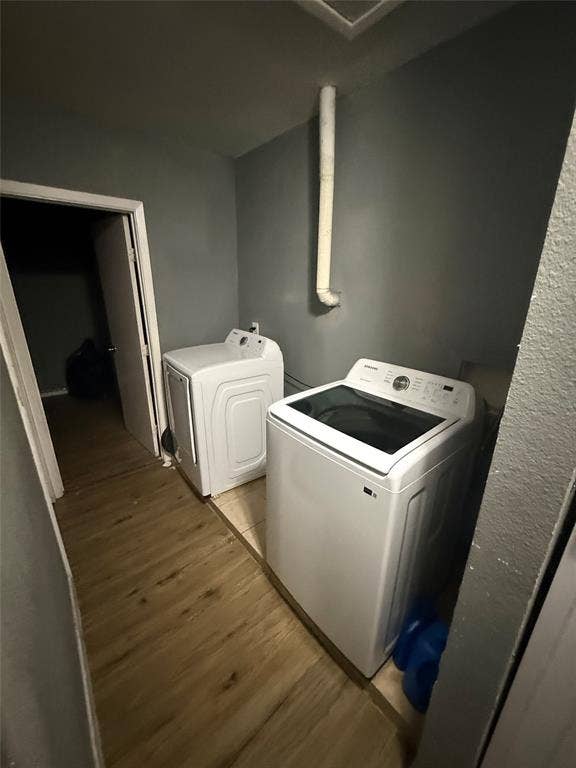 6036 Harrison Way, Watauga, TX 76148 Laundry room with light wood finished floors and washing machine and clothes dryer