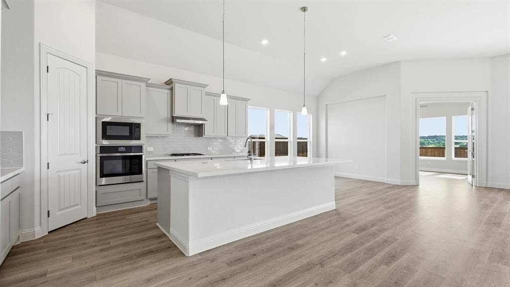 331 Fire Blade Drive, Aledo, TX 76008 Kitchen featuring a large island with a countertop, gray cabinetry, stainless steel appliances, and wood-finish flooring