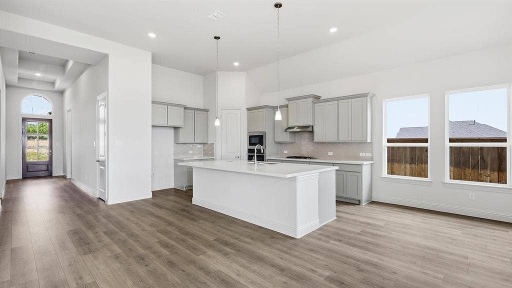 331 Fire Blade Drive, Aledo, TX 76008 Open-concept living area featuring wood-finish flooring, a contemporary kitchen island with a white countertop, light gray cabinetry, recessed lighting, and large windows