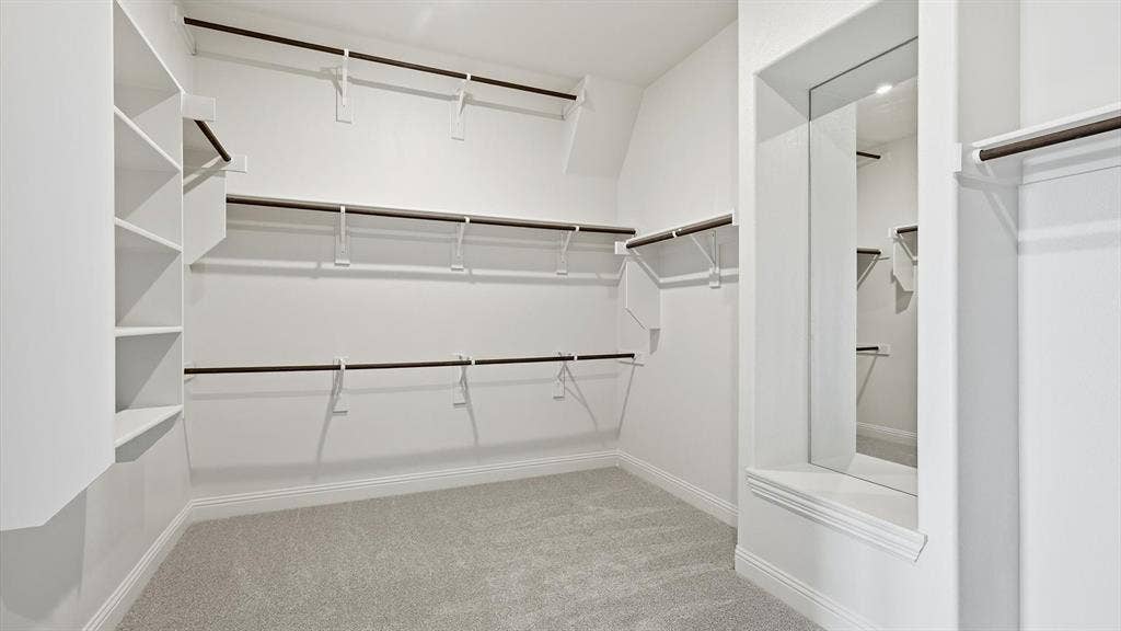 331 Fire Blade Drive, Aledo, TX 76008 Spacious walk-in closet featuring light grey carpeting, white walls, built-in shelving, multiple hanging rods, and a recessed full-length mirror