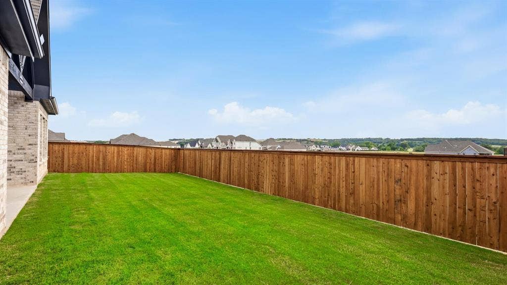 331 Fire Blade Drive, Aledo, TX 76008 Expansive backyard featuring a manicured lawn, a stained wood privacy fence, and a concrete patio area