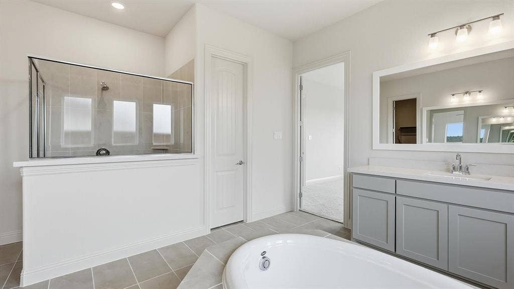 331 Fire Blade Drive, Aledo, TX 76008 Contemporary bathroom featuring a freestanding tub, a walk-in shower with glass enclosure and tiled walls, a vanity with a light gray cabinet and a rectangular mirror, and light-toned tile flooring