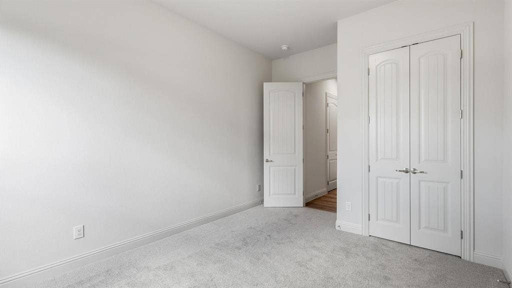 331 Fire Blade Drive, Aledo, TX 76008 Spacious room featuring light gray carpeting, white baseboards, and a pair of white paneled double doors with polished chrome hardware