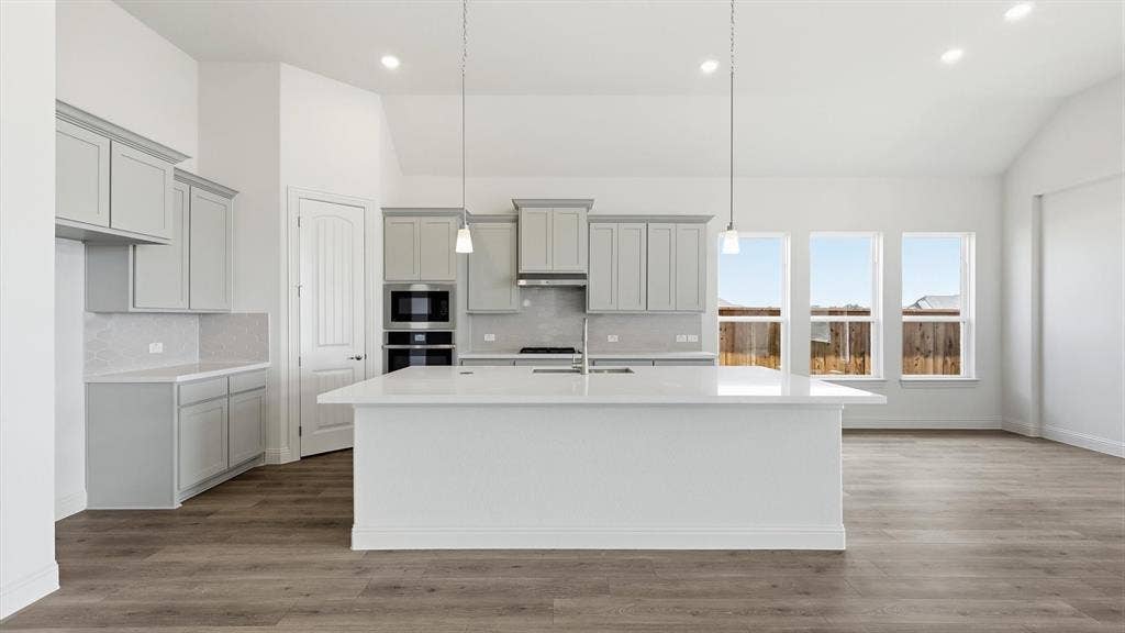 331 Fire Blade Drive, Aledo, TX 76008 Modern kitchen featuring a large central island with pendant lighting, light gray cabinetry, white countertops, and a full suite of built-in stainless steel appliances