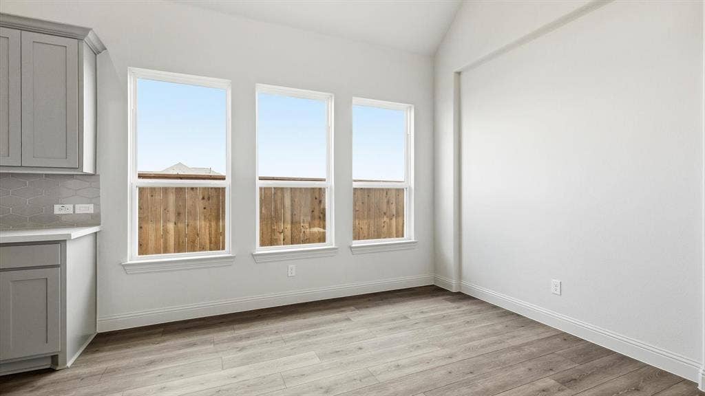 331 Fire Blade Drive, Aledo, TX 76008 Bright interior space featuring three large windows, a wood-finish floor, and vaulted ceilings