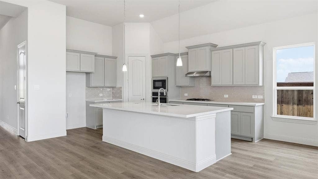 331 Fire Blade Drive, Aledo, TX 76008 Open-concept kitchen featuring an oversized island, light gray cabinetry, built-in stainless steel appliances, and wood-finish flooring