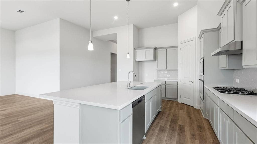 331 Fire Blade Drive, Aledo, TX 76008 Contemporary kitchen featuring a large island with a sink and pendant lighting, light gray cabinetry, stainless steel appliances, and wood-finish flooring
