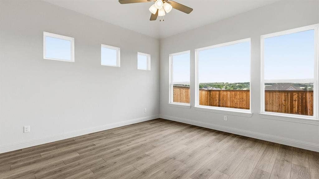 331 Fire Blade Drive, Aledo, TX 76008 Spacious room featuring wood-finish flooring, multiple windows providing ample ambient light, a ceiling fan with integrated lighting, and white baseboards