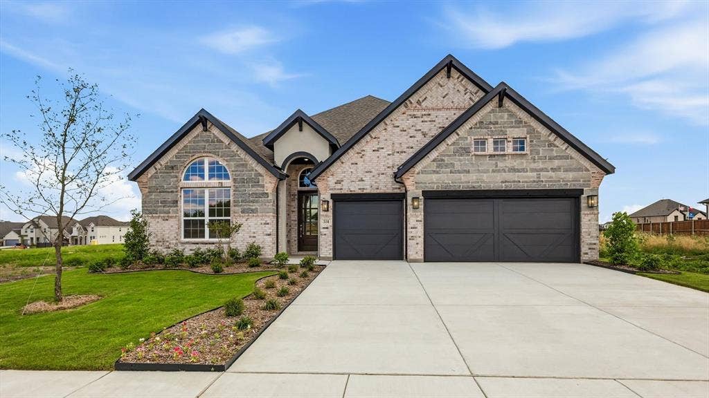331 Fire Blade Drive, Aledo, TX 76008 Contemporary architectural style featuring a multi-toned brick and stone facade, arched entry, two-car garage with carriage-style doors, a concrete driveway, and landscaped front yard with a young tree