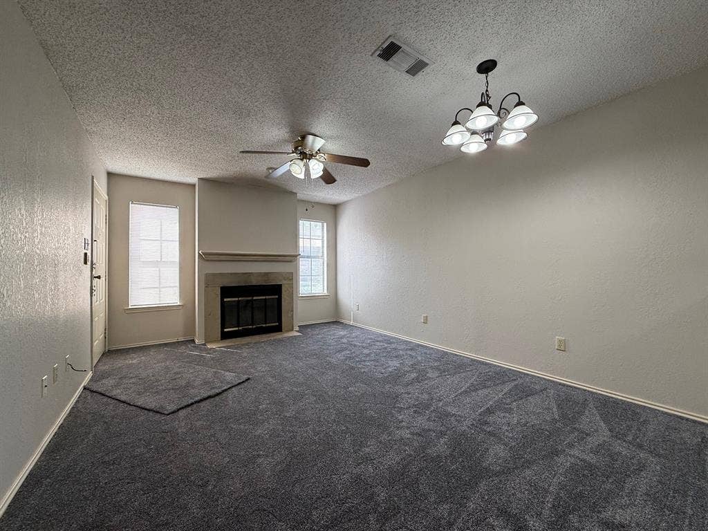 1723 Crest Grove Drive, #120B, Arlington, TX 76012 Unfurnished living room with a textured wall, dark colored carpet, ceiling fan, a fireplace, and a textured ceiling