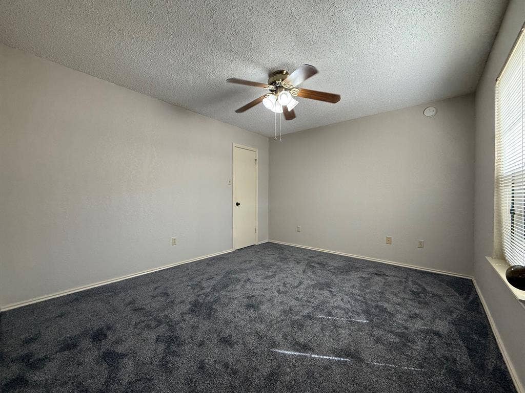 1723 Crest Grove Drive, #120B, Arlington, TX 76012 Unfurnished room with dark carpet, ceiling fan, and a textured ceiling