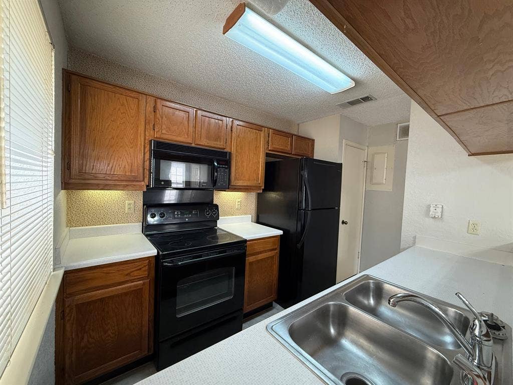 1723 Crest Grove Drive, #120B, Arlington, TX 76012 Kitchen with black appliances, wood finish cabinets, light countertops, and a textured ceiling
