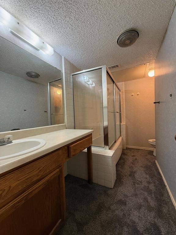 1723 Crest Grove Drive, #120B, Arlington, TX 76012 Bathroom with dark colored carpet, vanity, a textured ceiling, and bath / shower combo with glass door