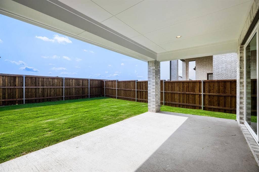 940 Heatherbrook Drive, Prosper, TX 75078 Expansive outdoor living area featuring a covered concrete patio, a spacious lawn, and a privacy fence