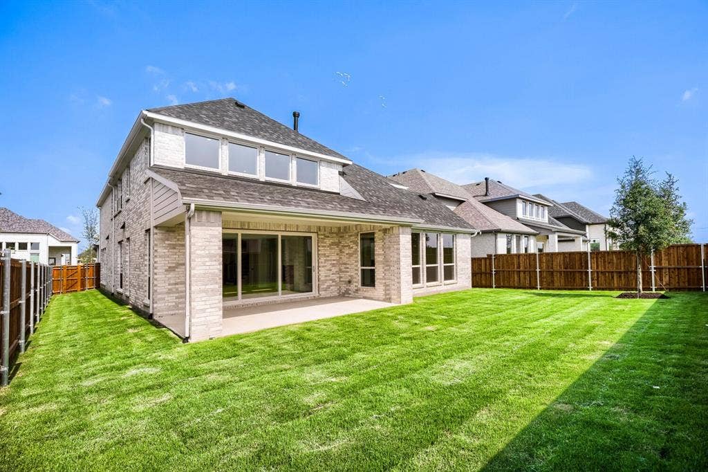 940 Heatherbrook Drive, Prosper, TX 75078 Expansive backyard featuring a concrete patio, a newly planted tree, and a stained wood privacy fence