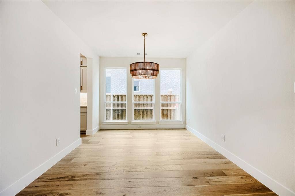 940 Heatherbrook Drive, Prosper, TX 75078 Dining area featuring a contemporary chandelier, three large windows, light wood-finish flooring, and white baseboards