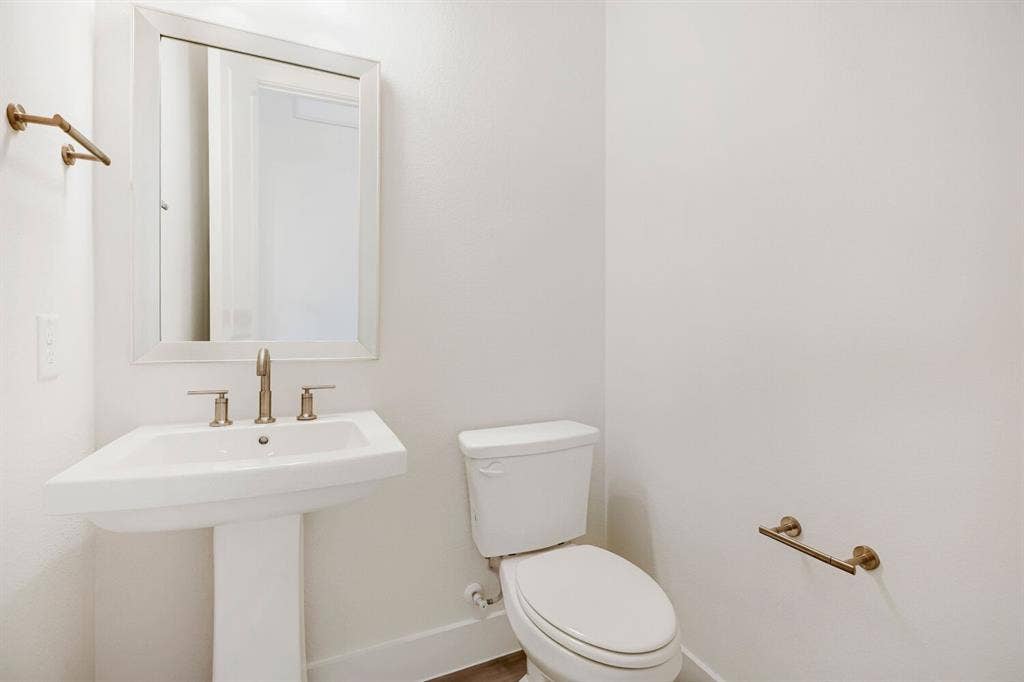 940 Heatherbrook Drive, Prosper, TX 75078 White pedestal sink with brushed nickel faucet, framed mirror, and coordinating bronze hardware