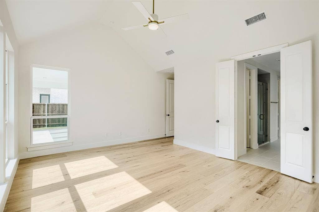 940 Heatherbrook Drive, Prosper, TX 75078 Spacious interior room featuring a vaulted ceiling with a modern ceiling fan, wood-finish flooring, and bright white walls