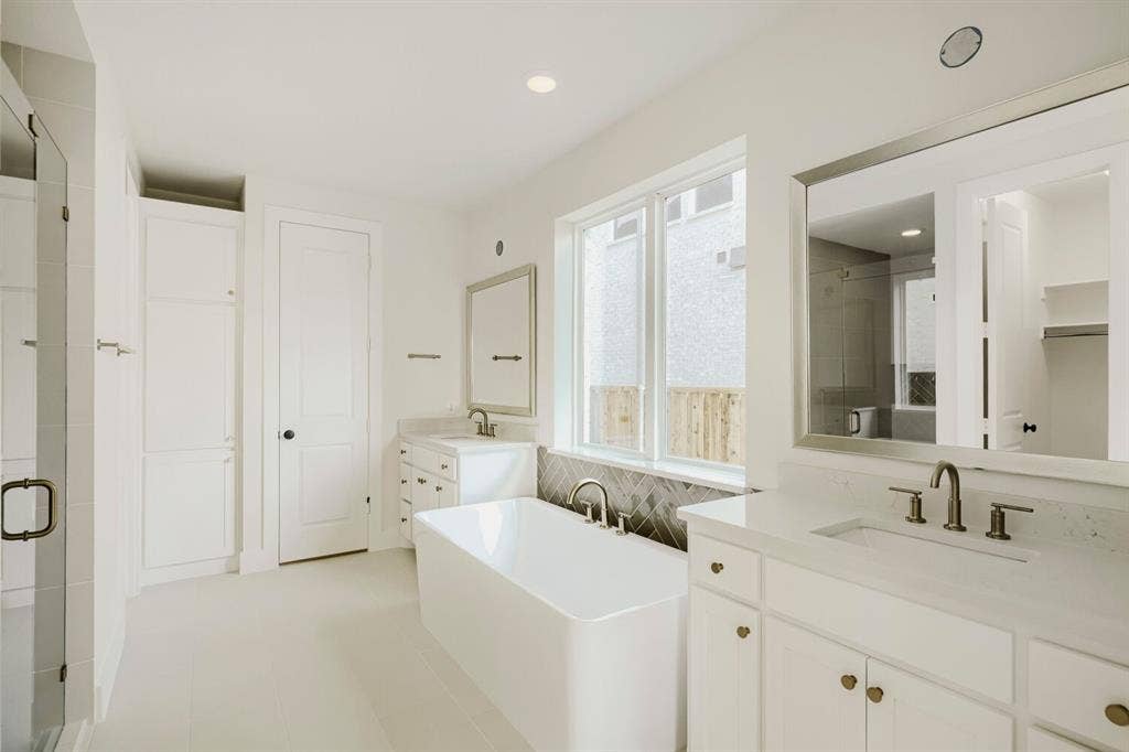 940 Heatherbrook Drive, Prosper, TX 75078 Contemporary bathroom featuring a freestanding soaking tub, dual vanity with undermount sinks, and a glass-enclosed shower