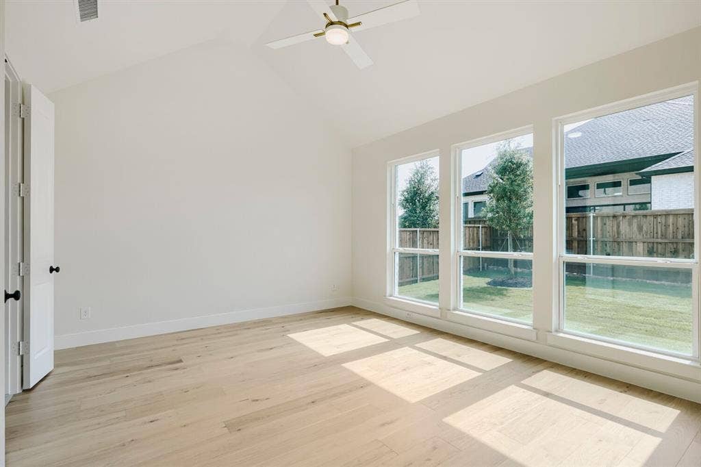 940 Heatherbrook Drive, Prosper, TX 75078 Vaulted ceiling room featuring light wood-finish flooring, three vertical windows, and a ceiling fan with integrated lighting
