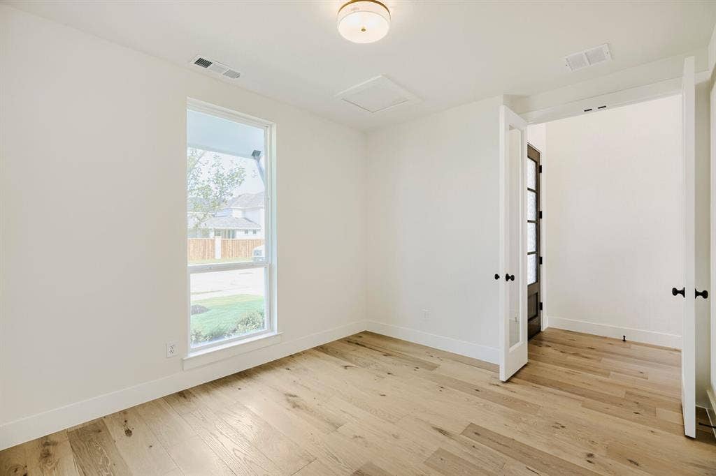 940 Heatherbrook Drive, Prosper, TX 75078 Bright room featuring wood-finish flooring, a large vertical window, white walls, and a contemporary ceiling light fixture