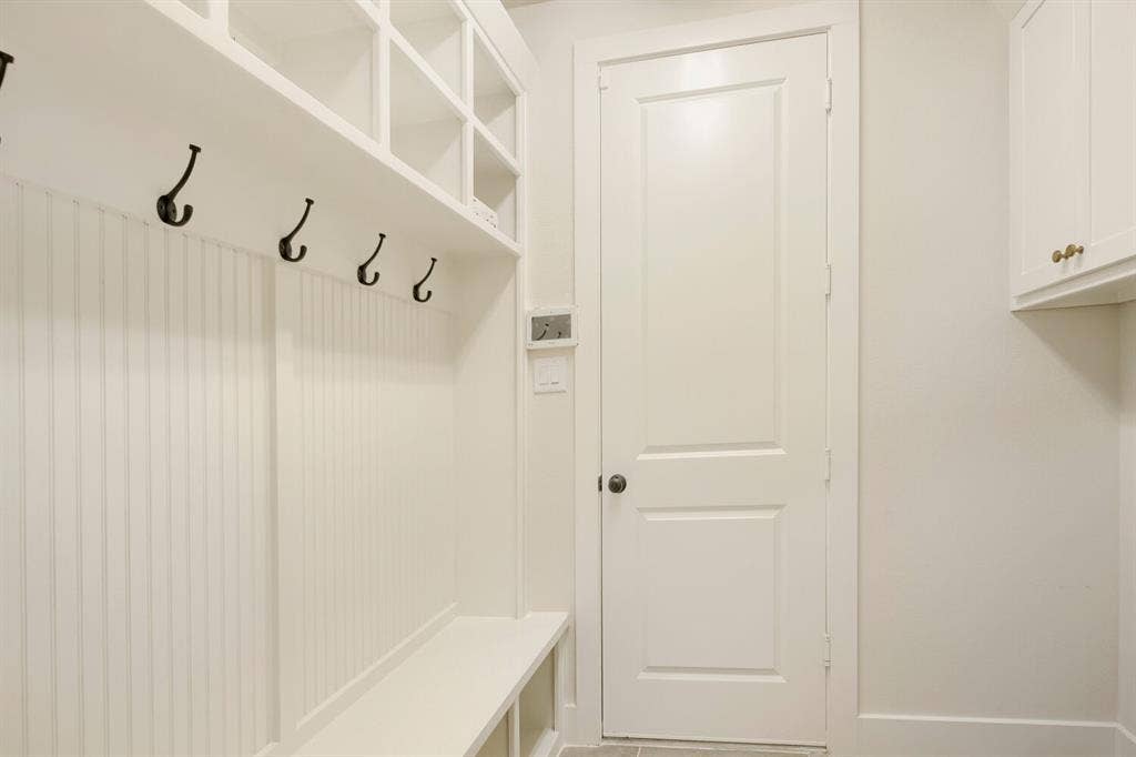 940 Heatherbrook Drive, Prosper, TX 75078 Built-in mudroom bench with cubby storage, beadboard paneling, and five black coat hooks