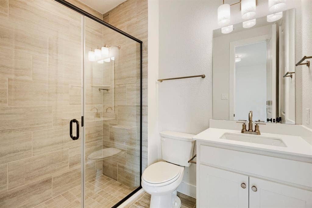 940 Heatherbrook Drive, Prosper, TX 75078 Modern bathroom featuring a glass-enclosed shower with tile surround and integrated bench
